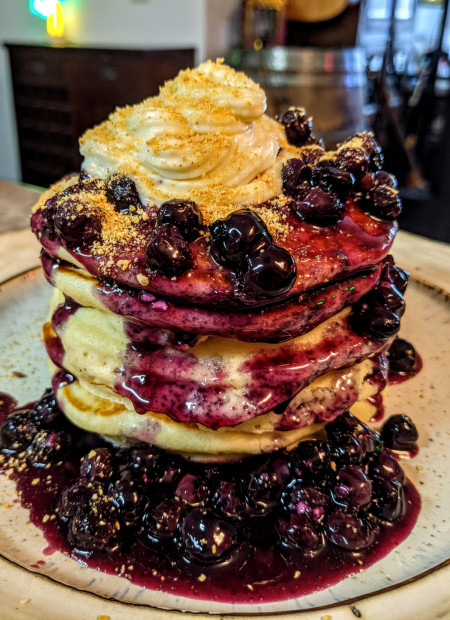 Blueberry pancakes with blueberries compote topped with banana cream cheese frosting and graham cracker crumbs