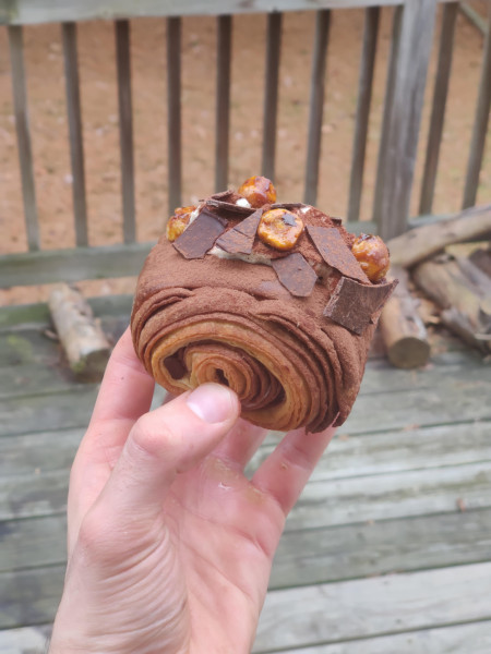 Pain au Chocolat filled with vanilla cream, topped with chocolate shards and caramelized hazelnuts
