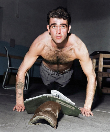 Actor Sean Connery reading while doing push-ups, 1957