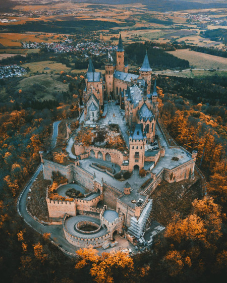 Hohenzollern Castle on a hilltop overlooking the autumn forest and the villages beyond, Bisingen, Baden-Württemberg, Germany