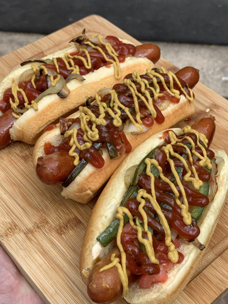 Grilled beef hotdogs with tomato, grilled onions, and jalapeños