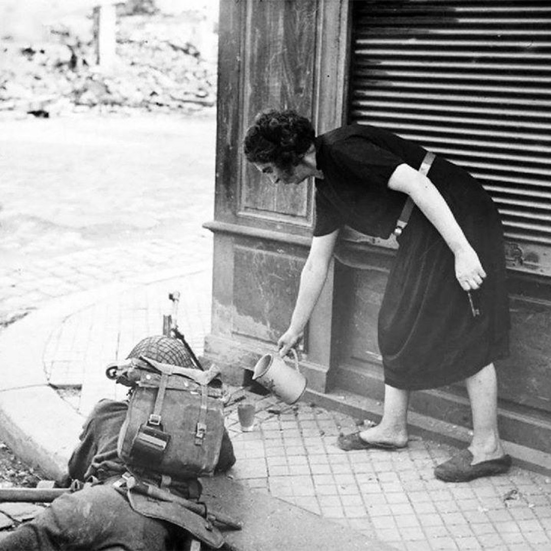 French woman pouring tea for a British soldier fighting in Normandy 1944