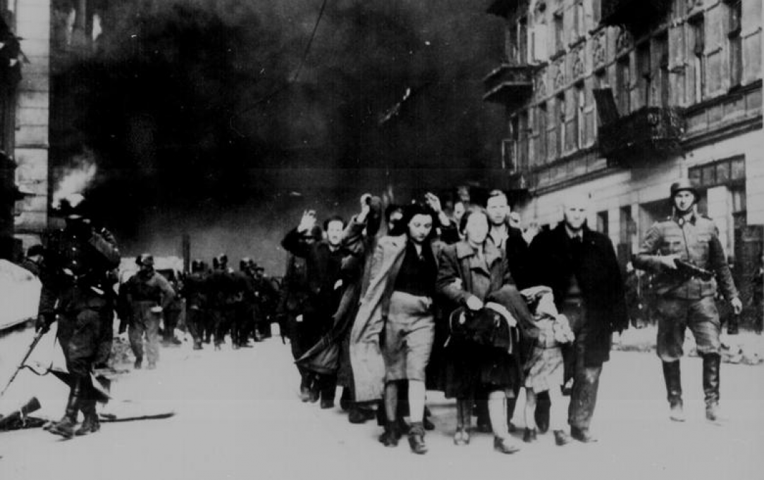 Jewish civilians are led down a street by German soldiers during the destruction of the Warsaw Ghetto, in Poland, in 1943