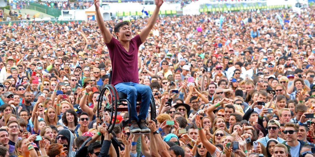 Crowd at festival help man in wheelchair see the show