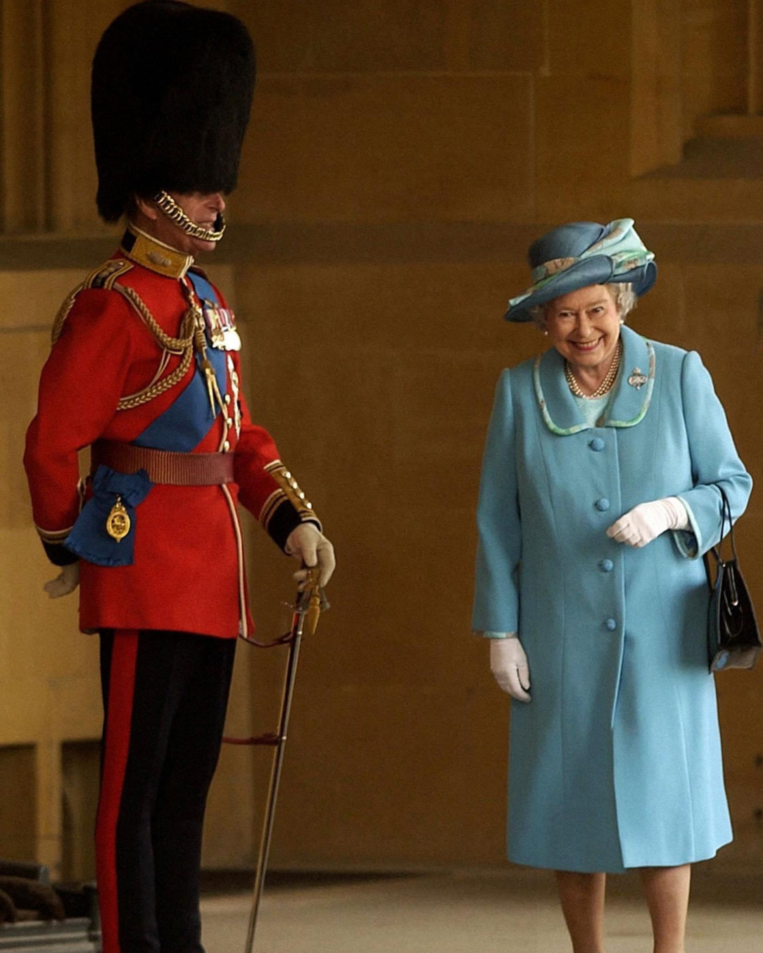 Queen Elizabeth II giggling as she walks past her husband Prince Philip in his full uniform