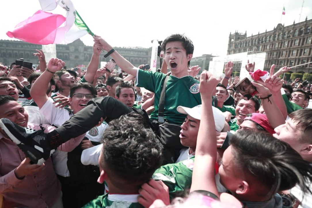 A group of Mexican fans carrying a South Korean fan after a South Korean win secures Mexico a spot in the knockout stage of the World Cup