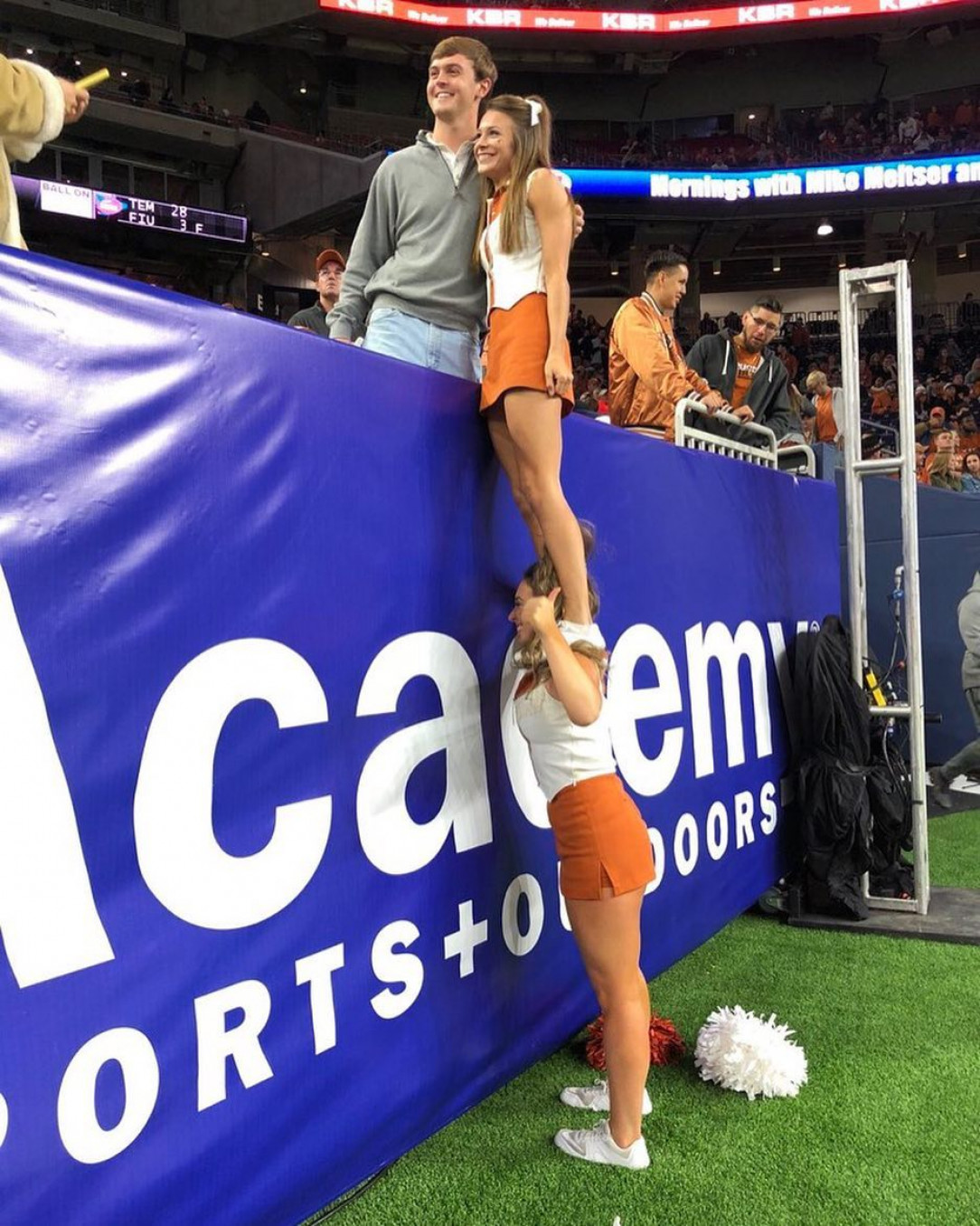 Cheerleader helping a friend out for a picture with a fan