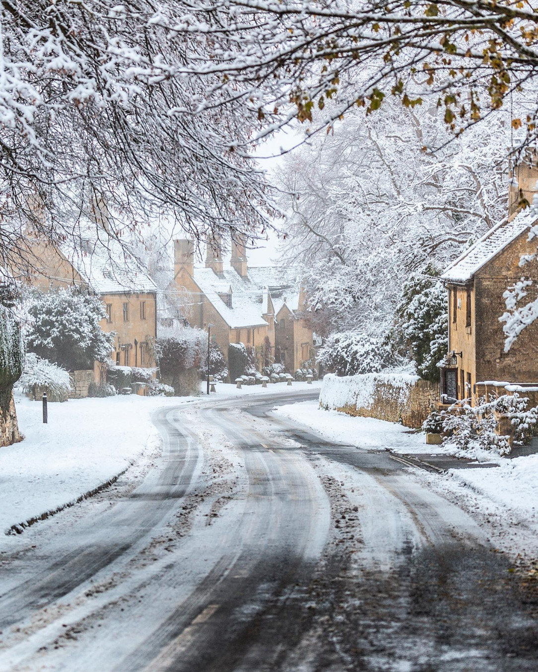 Snow covered branches over the road in Broadway, a Cotswolds village in Worcestershire, England