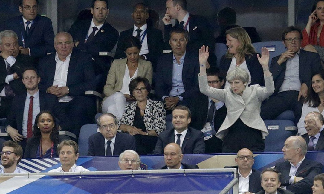 Theresa May tries to participate in the human wave at the France-England match but she seriously misjudges the timing