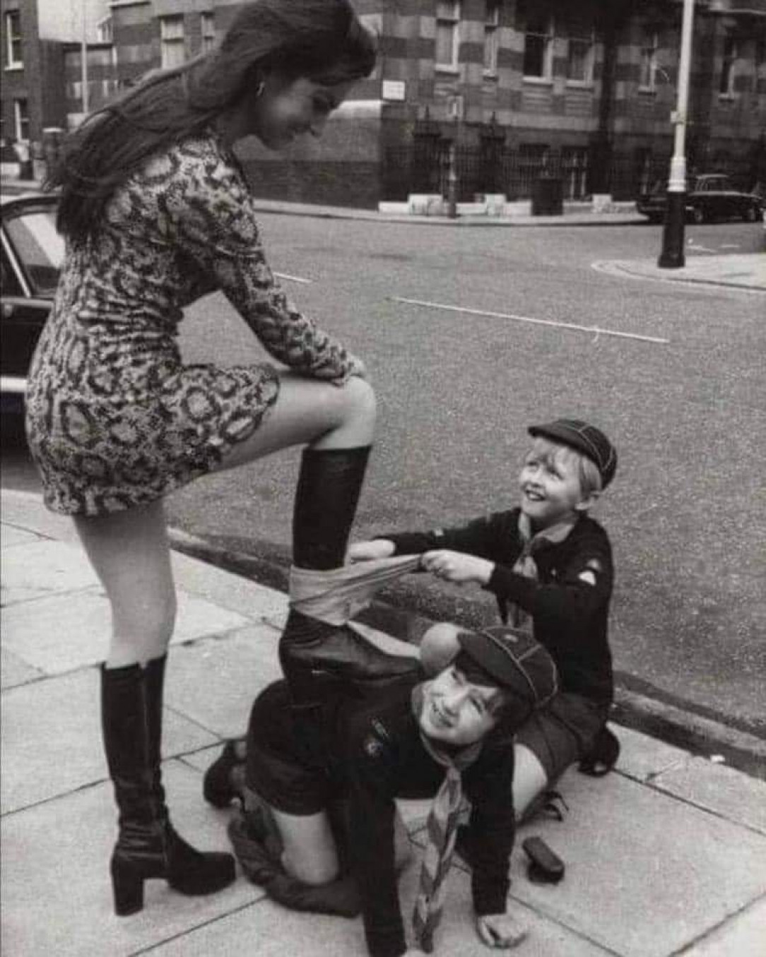 Actress Caroline Munroe getting her boots shined by Cub Scouts in London, 1972
