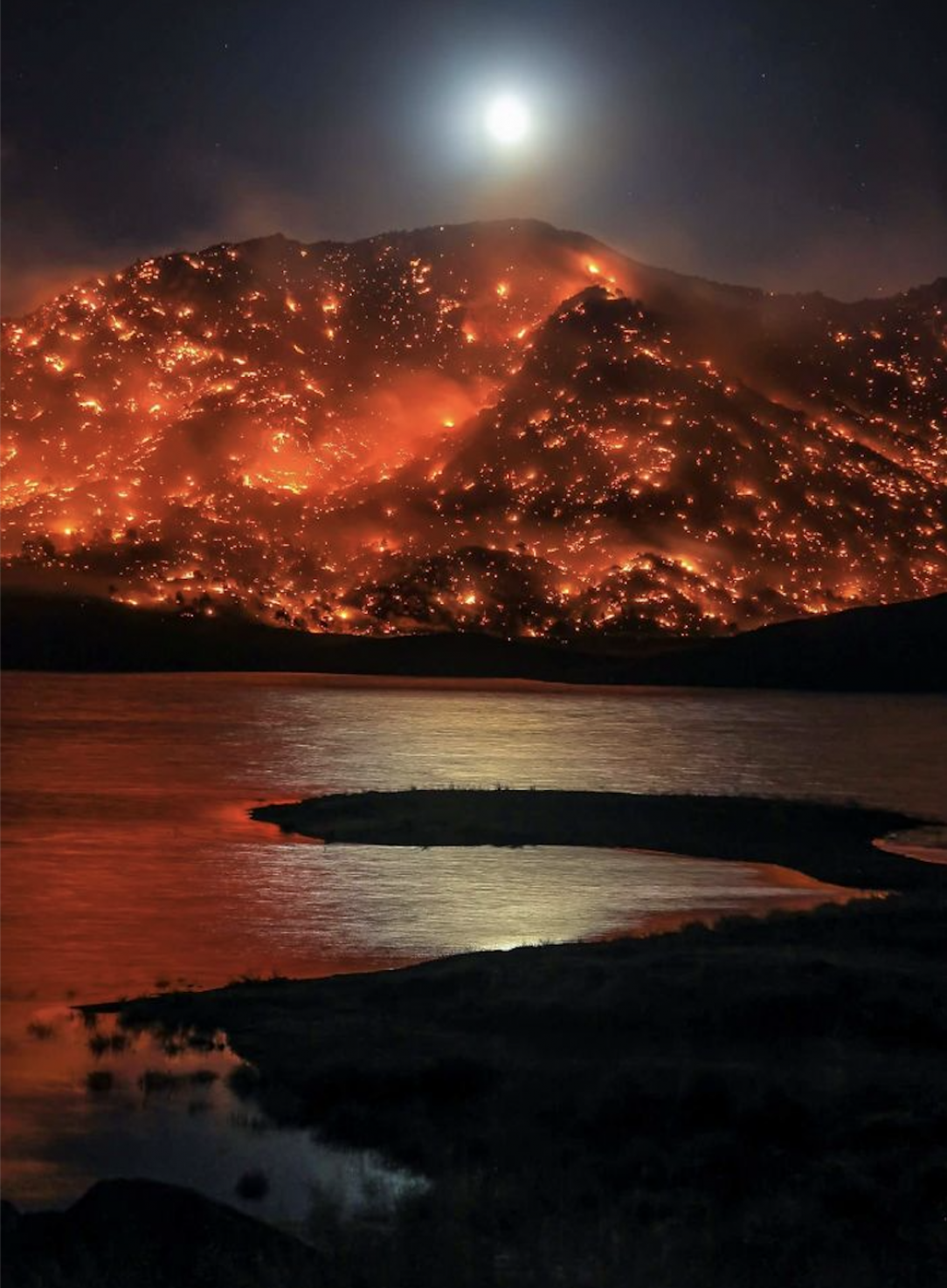 The moon rising over a hill in California, engulfed in a wildfire