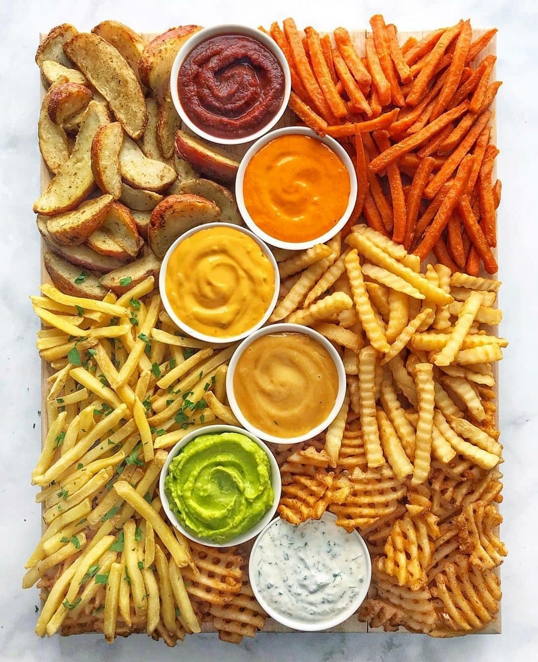 Perfectly aligned fries and sauce with a perfect mix of colours on a board
